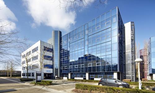 Exterior view of the modern office building at Bruistensingel 400, Den Bosch, highlighting its sleek glass facade and parking area, ideal for office space rental.