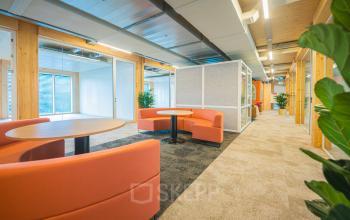 Bright and modern workspace with orange seating and round tables, ideal for meetings or breakouts at Hambakenwetering 1-kr, Den Bosch. Perfect for office space rental.