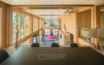 Open-floor workspace with large wooden interiors, glass walls, and modern furnishings, perfect for office space rental in Den Bosch.