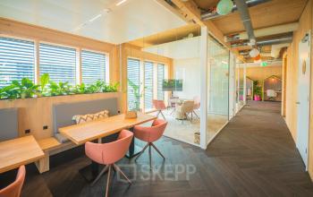 Modern office space at Hambakenwetering 1-kr, Den Bosch featuring inviting workspaces with wooden interiors, colorful seating, and natural light. Ideal for office space rental.