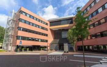 Modern exterior of an office building at Utopialaan 22, Den Bosch, featuring contemporary architecture and a welcoming entrance. Ideal for office space rental with ample natural light and professional appeal.