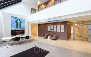 Spacious and modern entrance area at Utopialaan 22 in Den Bosch, featuring stylish seating and artistic wall decor, ideal for a welcoming environment in an office space rental.