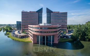 Modern office building at Utopialaan 22, Den Bosch, surrounded by water and greenery, showcasing a unique architectural design, available as an office space rental.