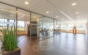 Modern office interior at Utopialaan 22, Den Bosch, featuring glass-walled conference rooms and abundant natural light, ideal for office space rental.