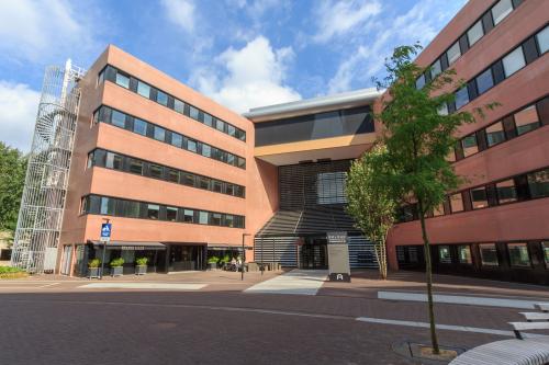 Modern exterior of an office building at Utopialaan 22, Den Bosch, featuring contemporary architecture and a welcoming entrance. Ideal for office space rental with ample natural light and professional appeal.