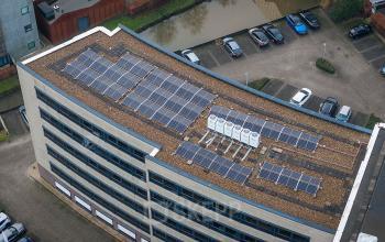 Exterior view of Pettelaarpark 110 office building in Den Bosch, showcasing rooftop solar panels and adjacent parking area. Ideal for those seeking office space rental with sustainable features.