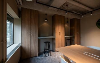 Modern office space with wooden cabinets and bar seating at Pettelaarpark 110, Den Bosch. Ideal for those looking for office space rental with a sleek design and functional furniture.