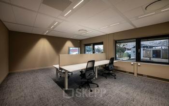 Modern office space rental at Pettelaarpark 110 in Den Bosch featuring a minimalistic design, with two workstations and large windows for natural light.