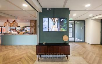 Modern office space at Pettelaarpark 110 in Den Bosch featuring stylish decor and a welcoming atmosphere, ideal for office space rental. Includes a central console and visible hallway.