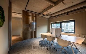 Modern office space at Pettelaarpark 110, Den Bosch, featuring a well-lit meeting area with a wooden table and swivel chairs, available for office space rental.