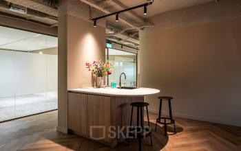 Stylish office pantry area at Pettelaarpark 110 in Den Bosch, featuring a modern counter with bar stools and subtle lighting, ideal for informal meetings. Great option for office space rental.