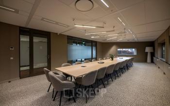 Spacious conference room at Pettelaarpark 110 in Den Bosch, featuring a long table with comfortable chairs, ideal for meetings. Perfect for office space rental.