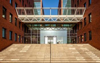 Exterior view of the office building at Hambakenwetering 5, Den Bosch. The building features a modern glass entrance and red brick facade. Office to rent for business opportunities.