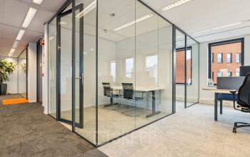Modern office space rental in Den Bosch with glass-walled meeting room, sleek desks, and abundant natural light. Located at Hambakenwetering 5, it's ideal for professional work environments.