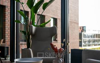 Modern office space rental at Hambakenwetering 5, Den Bosch. Features large windows and stylish furniture, ideal for a cozy lounge area.