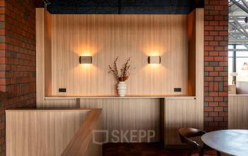 Cozy furnished office space at Hambakenwetering 5 in Den Bosch, featuring warm lighting and a decorative vase on a wooden counter, perfect for office space rental.