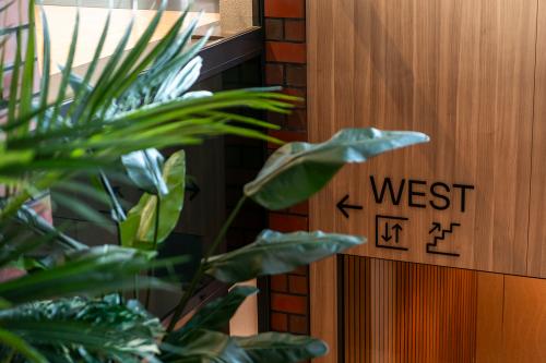 Interior view of Hambakenwetering 5 in Den Bosch, featuring a wooden wall with directional signage and lush green plants, ideal for office space rental.