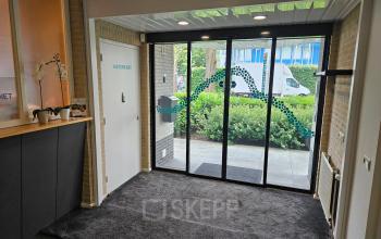 Entrance area with glass doors at office space for rent at Hambakenwetering 18, Den Bosch, featuring a simple reception area and view to the outside.