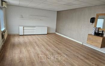 Unfurnished office space with wooden floors and white walls at Hambakenwetering 18, Den Bosch, ideal for office space rental. Minimalist design includes a small cabinet and mirror.