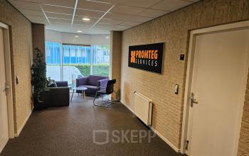 Modern office entrance at Hambakenwetering 18, Den Bosch, featuring a lounge area with chairs and a company sign. Ideal for office space rental.