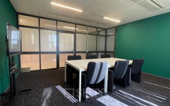 Spacious meeting room with green walls at Bruistensingel 500 in Den Bosch, featuring a large table, comfortable chairs, and a presentation screen, ideal for office space rental.