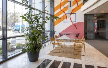 Modern office entrance at Bruistensingel 500, Den Bosch, with vibrant wall art, glass table, and stylish seating for a dynamic first impression.