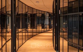 Curved glass-walled office corridor at Reitschweg 1, Den Bosch, ideal for office space rental.