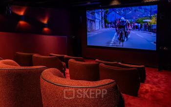 A cozy office space in Den Bosch features a small theater with plush seating and a large screen, ideal for presentations or events.