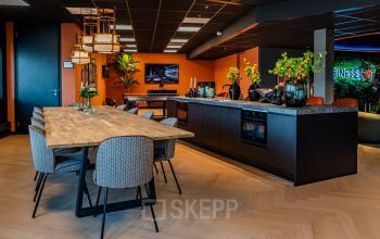 Modern office kitchen with a wooden dining table, stylish chairs, and a sleek kitchenette at Reitschweg 1, Den Bosch, ideal for office space rental.