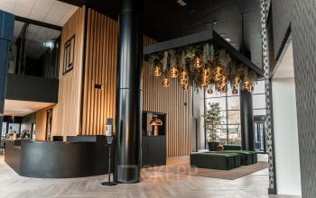Modern office lobby at Reitschweg 1, Den Bosch, featuring stylish hanging lights and green seating area, available for office space rental.