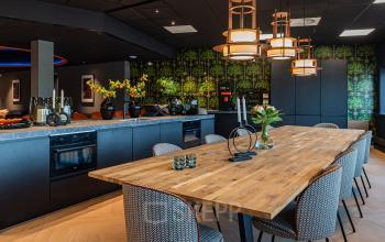 Modern, stylish office space with a wooden table surrounded by patterned chairs and ambient lighting, perfect for an office to rent at Reitschweg 1, Den Bosch.
