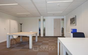 Modern office space rental at Koninginnegracht 19, The Hague Center, with a comfortable meeting table, chairs, ample lighting, and clean design.
