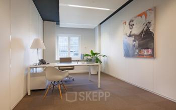 Modern and well-lit office space rental at Koninginnegracht 19 in The Hague Center, featuring a stylish desk, chair, and vibrant artwork.