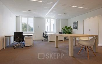 Contemporary office space rental at Koninginnegracht 19, The Hague Center, featuring a wooden desk, chairs, and ample natural light.
