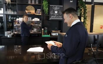 Businessman in a suit at a modern office space rental at Koninginnegracht 19, The Hague Center, being served coffee by staff.