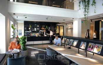 Contemporary office lounge at Koninginnegracht 19 with individuals engaged in business activities, ideal for an office space rental at The Hague Center.