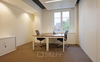 Modern office space rental at Koninginnegracht 19, The Hague Center, with a desk, chairs, and ample natural light.