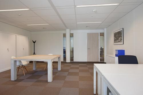 Modern office space rental at Koninginnegracht 19, The Hague Center, with a comfortable meeting table, chairs, ample lighting, and clean design.