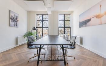 Bright office at Zeestraat 100, The Hague Center, featuring large windows, a sleek table, and stylish chairs. Perfect spot for your next office space rental.