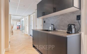 Compact office pantry at Zeestraat 100, The Hague Center, ideal for office space rental. Features modern fixtures and wood flooring.