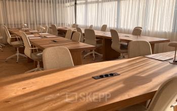 Spacious interior with natural light at Zeestraat 100, The Hague Center, ideal for office space rental. Wooden desks and comfortable chairs are arranged for collaborative work.