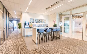 Modern office space rental at Koningin Julianaplein 10, The Hague Center, featuring a furnished area with a high table and stools, ideal for collaboration and meetings.