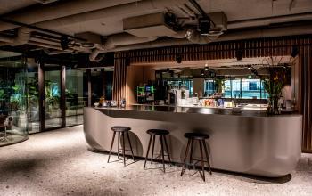 Modern furnished office space for rent at Anna van Buerenplein 41, The Hague Center, featuring a sleek counter and seating area.