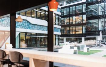 View from an office space rental at Anna van Buerenplein 41, The Hague Center, overlooking a modern outdoor area with seating.