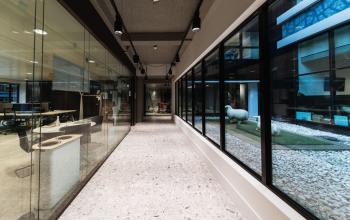 Modern office space with glass walls, showing a hallway and adjacent work area at Anna van Buerenplein 41, The Hague Center, available for office space rental.