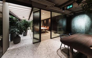 Stylish office space with glass-enclosed meeting area and plants at Anna van Buerenplein 41, ideal for office space rental in The Hague Center.