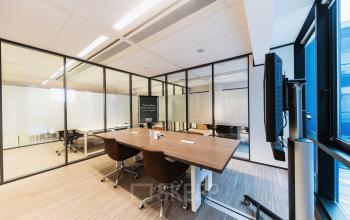 Modern office space at Anna van Buerenplein 41, The Hague Center, featuring a sleek conference table with chairs and a wall-mounted monitor ideal for office space rental.