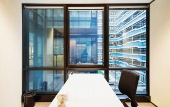 Bright office space at Anna van Buerenplein 41 in The Hague Center, featuring a large window with a modern city view, available for rent. Includes a sleek table and office chair.