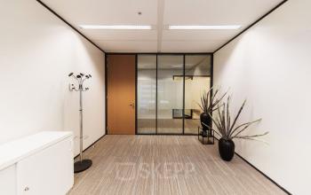 A modern, unfurnished office space available for rent at Anna van Buerenplein 41, featuring a clean design with glass partitions. Ideal for your next office space rental in The Hague Center.