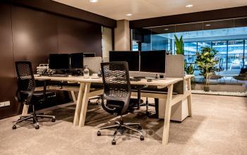 Modern office space available for rent at Anna van Buerenplein 41, The Hague Center, featuring workstations with computers and ergonomic chairs in a stylish, furnished interior.